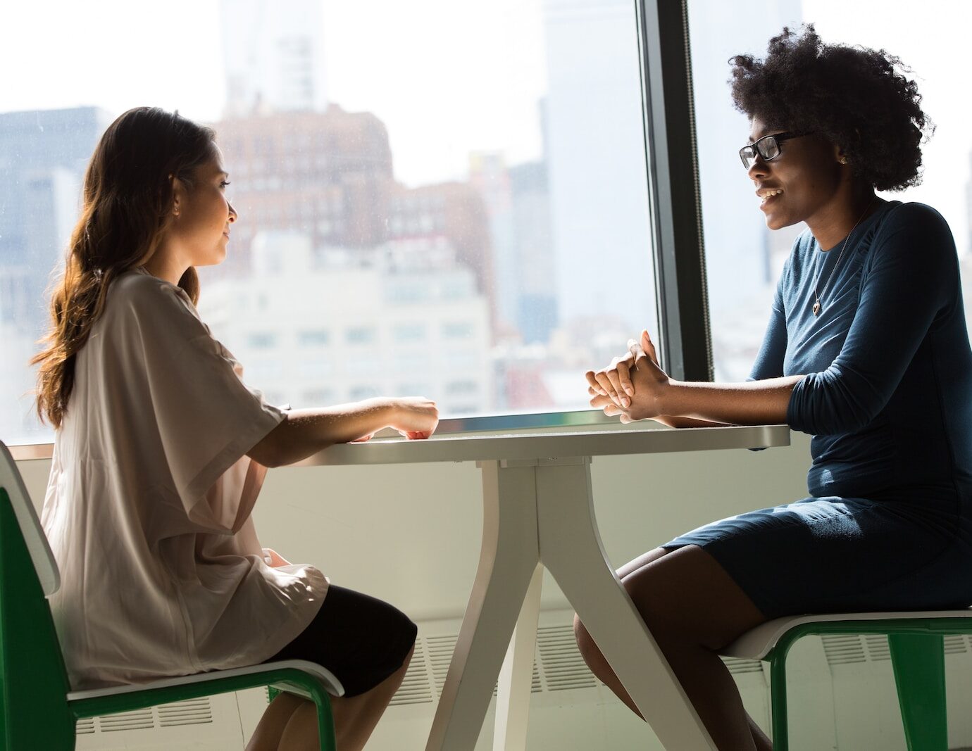 two women sitting beside table and talking